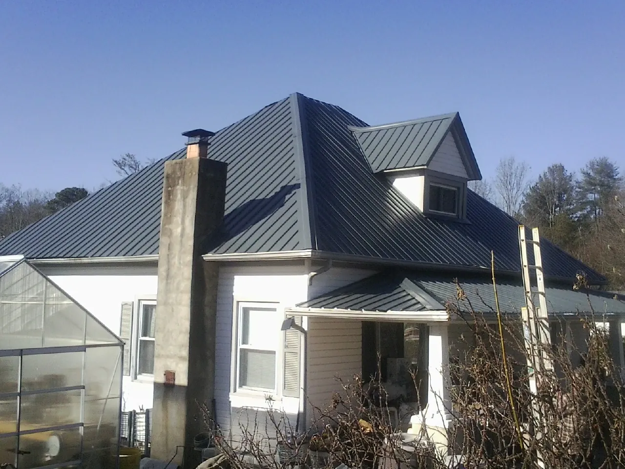 Dark blue standing seam metal roof on a white farmhouse with dormer — Slate & Tile Roof Repair by Roofing Brothers in Coalmont
