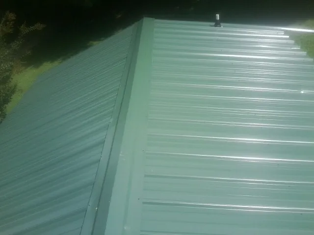New green metal panels meeting at the ridge of a roof — Flat Roof Repair work by our crew in Coalmont