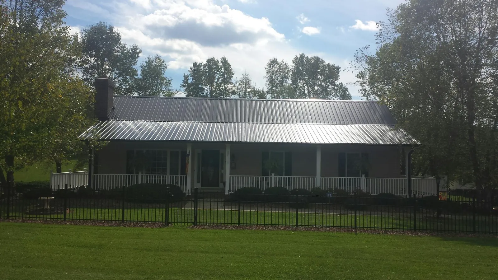 Gray metal roof on a brick ranch with a full width front porch — Gutter Guard Installation work by our crew in Coalmont